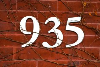 Photo of white large numbers 935 on a brick building with vines - cropped to just the numbers.